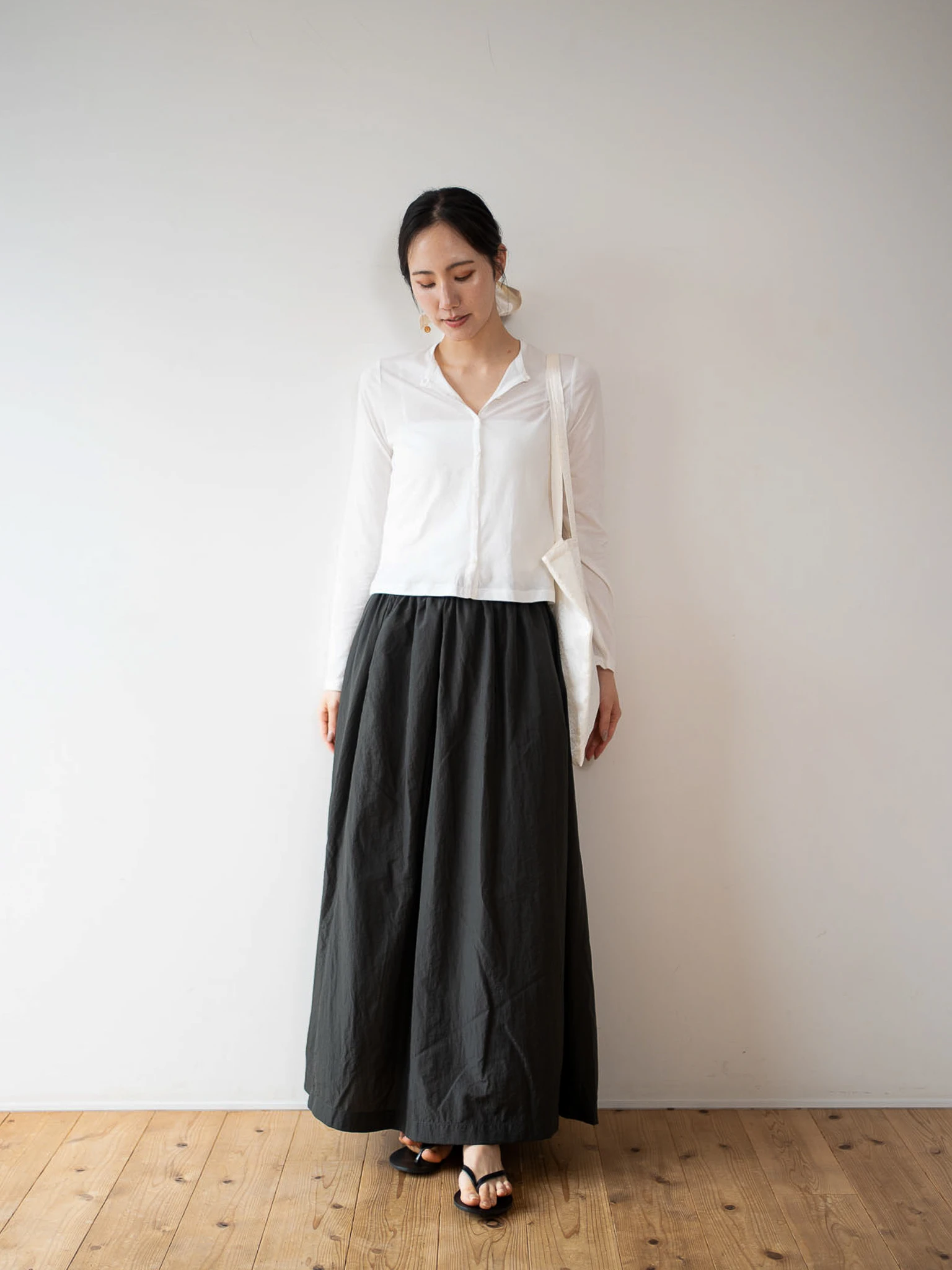 白色のsheer cotton cardiganと黒のスカートを着た女性