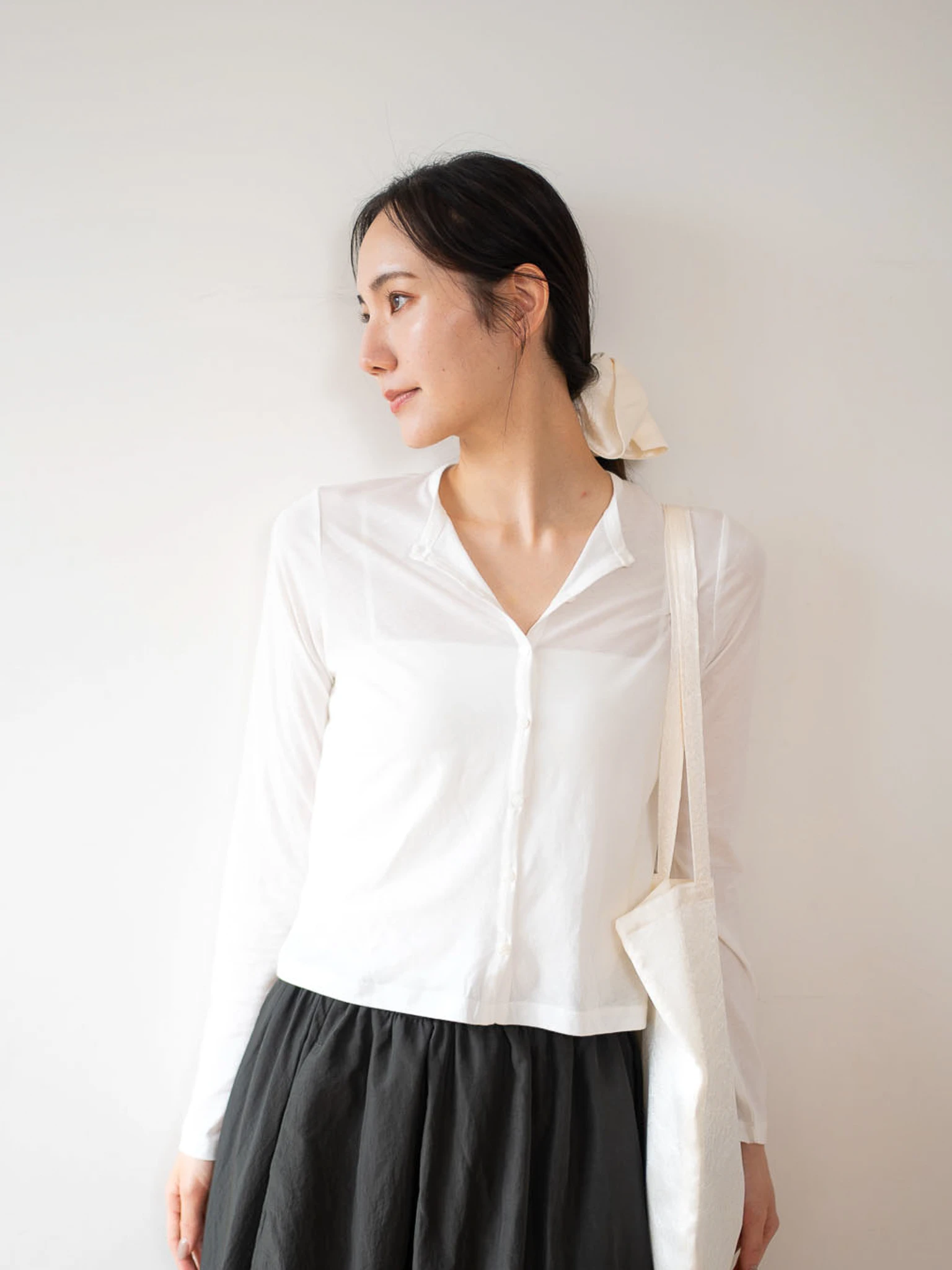 白色のsheer cotton cardiganを着てUKAYのトートバッグを持っている女性